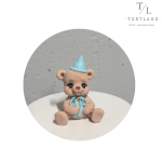 Шоколадна фігурка "'Ведмедик коричневий в ковпачку з блакитним бантиком"